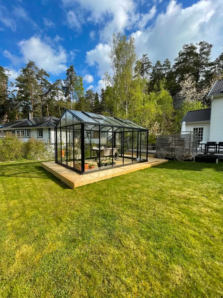 Färdigt trädäck som bildar underlag för ett växthus i trädgården
